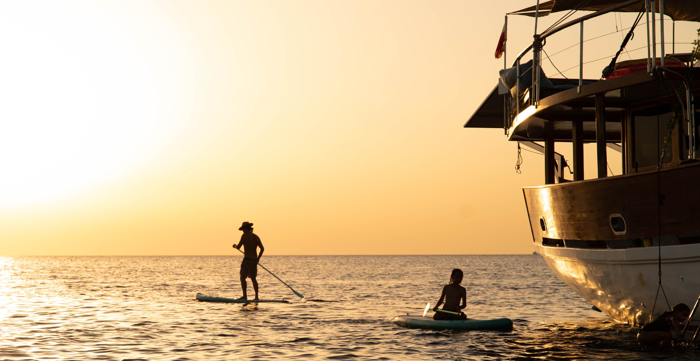 Boat on water with two people on paddle boards