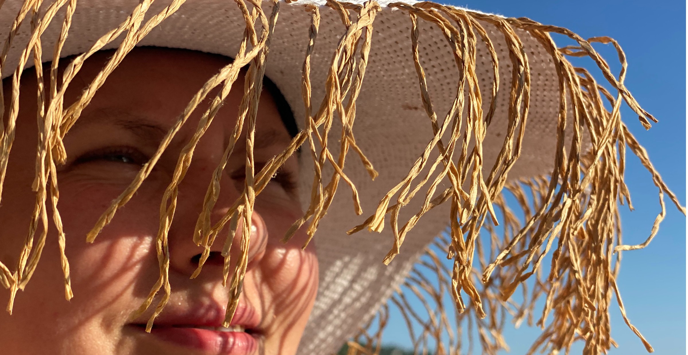 Lady in straw hat looking to the right on a sunny day